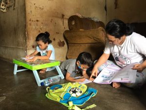 Seorang Kakak sedang mengajari Adik adiknya dalam situasi pandemi Covid19 dengan program belajar dirumah atau daring.